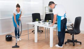 Cleaners in office cleaning white desk and wooden floor